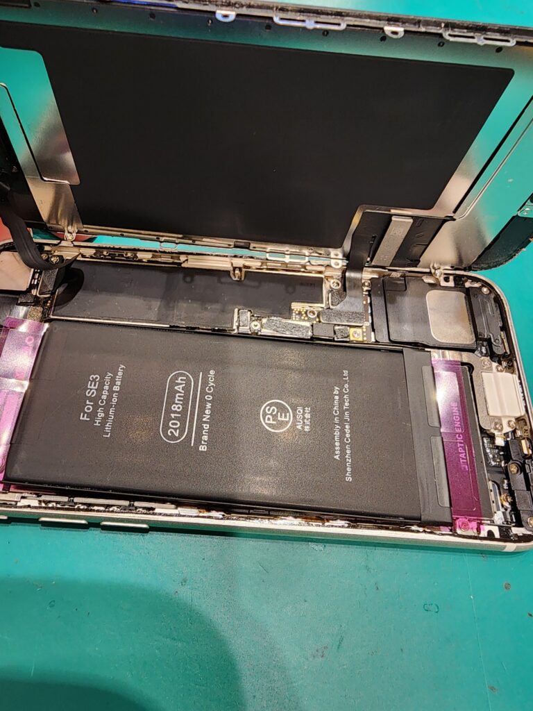 新しいバッテリーを仮付けしたiPhoneSE3