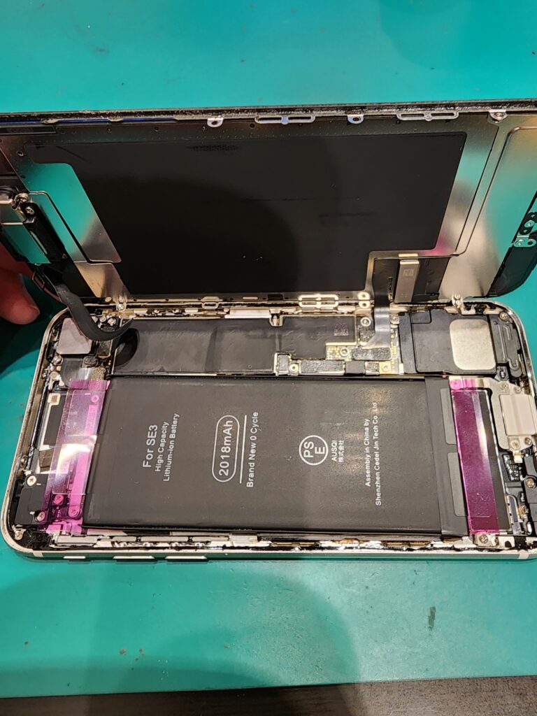 新しいバッテリーを仮付けしたiPhoneSE3